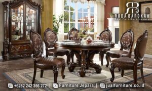 Meja Makan Bundar Mewah Sovrano Nuansa Timeless FS-930, terbuat dari kayu jati dengan kaki meja ukiran elegan dan pelapis kain bludru, sempurna untuk menghias ruang makan Anda.